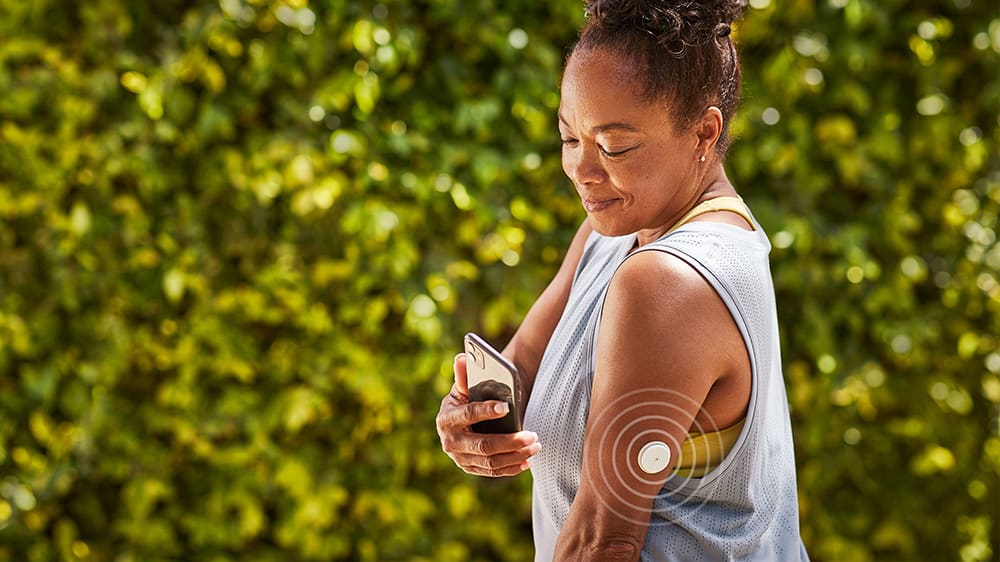 Woman using phone and sensor-based glucose monitoring system