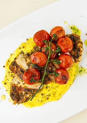 chicken breast on bed of sweetcorn puree with cherry tomatoes on top