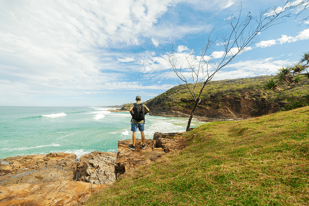 Rear view of man looking out at sea on hike