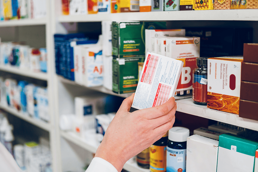 Hand selecting medicine from shelf of medications