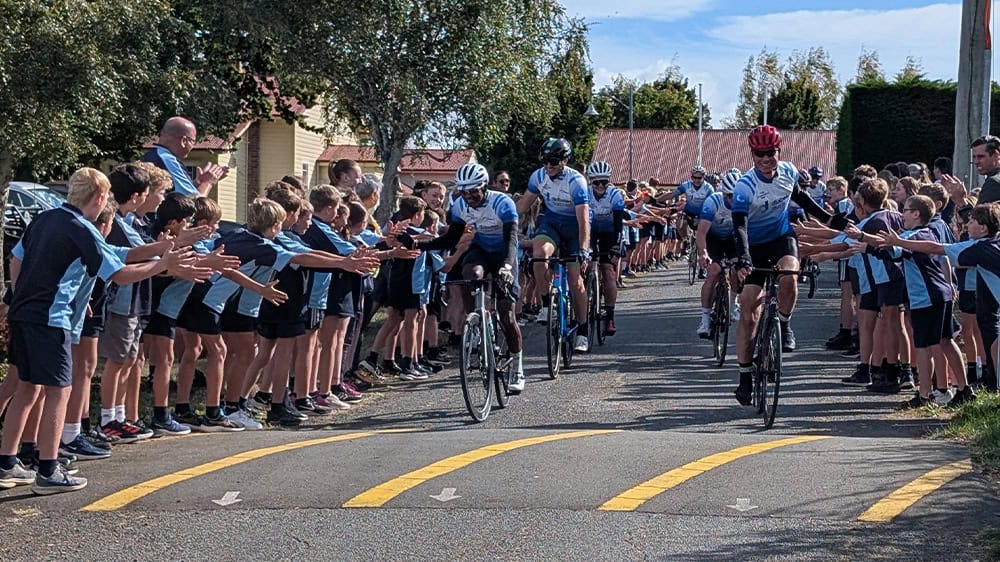 Pollie Pedal cyclists led by Tasmania's Deputy Premier Guy Barnett are waved out of Hagley Farm School grounds by students as they start the three-day fundraising event.