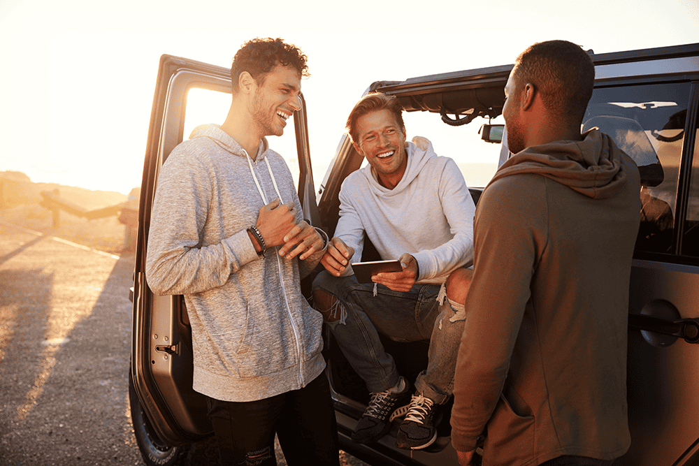 three men on a road trip chatting by their car